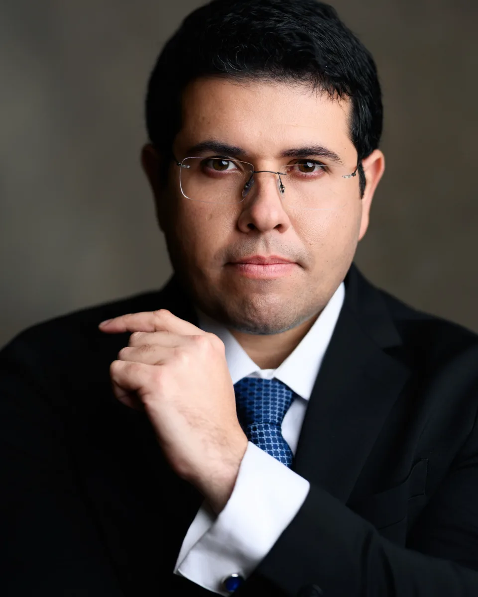Lucas Marins, advogado, de terno escuro e gravata azul, olhando para a câmera